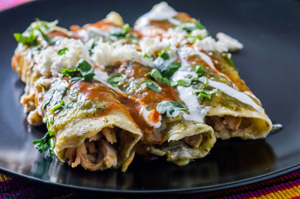 Enchiladas Verdes, or green enchiladas, tortillas filled with chicken and topped with green sauce, cheese and sour cream