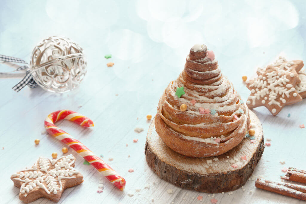 Close-up homemade sweet Christmas cinnamon roll bun white wood new year table.