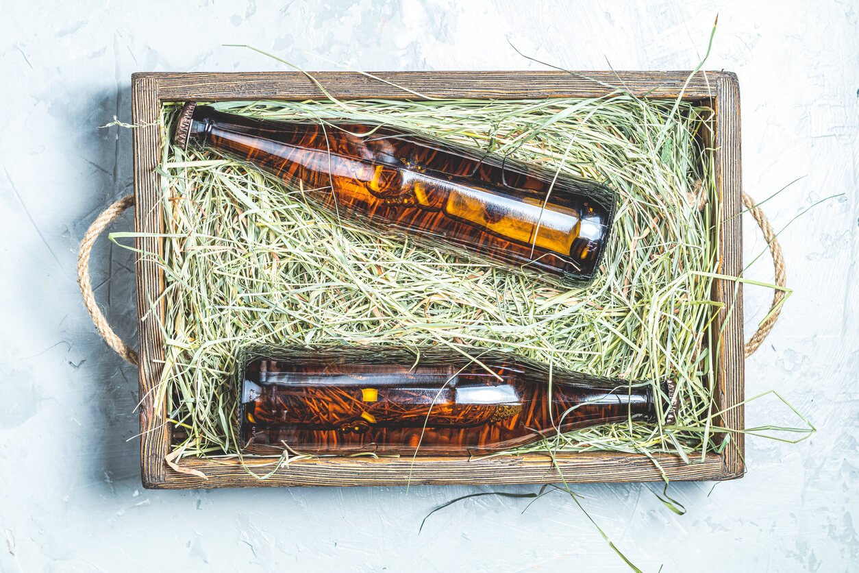 Craft beer with dried grass in wooden box on gray concrete surface background