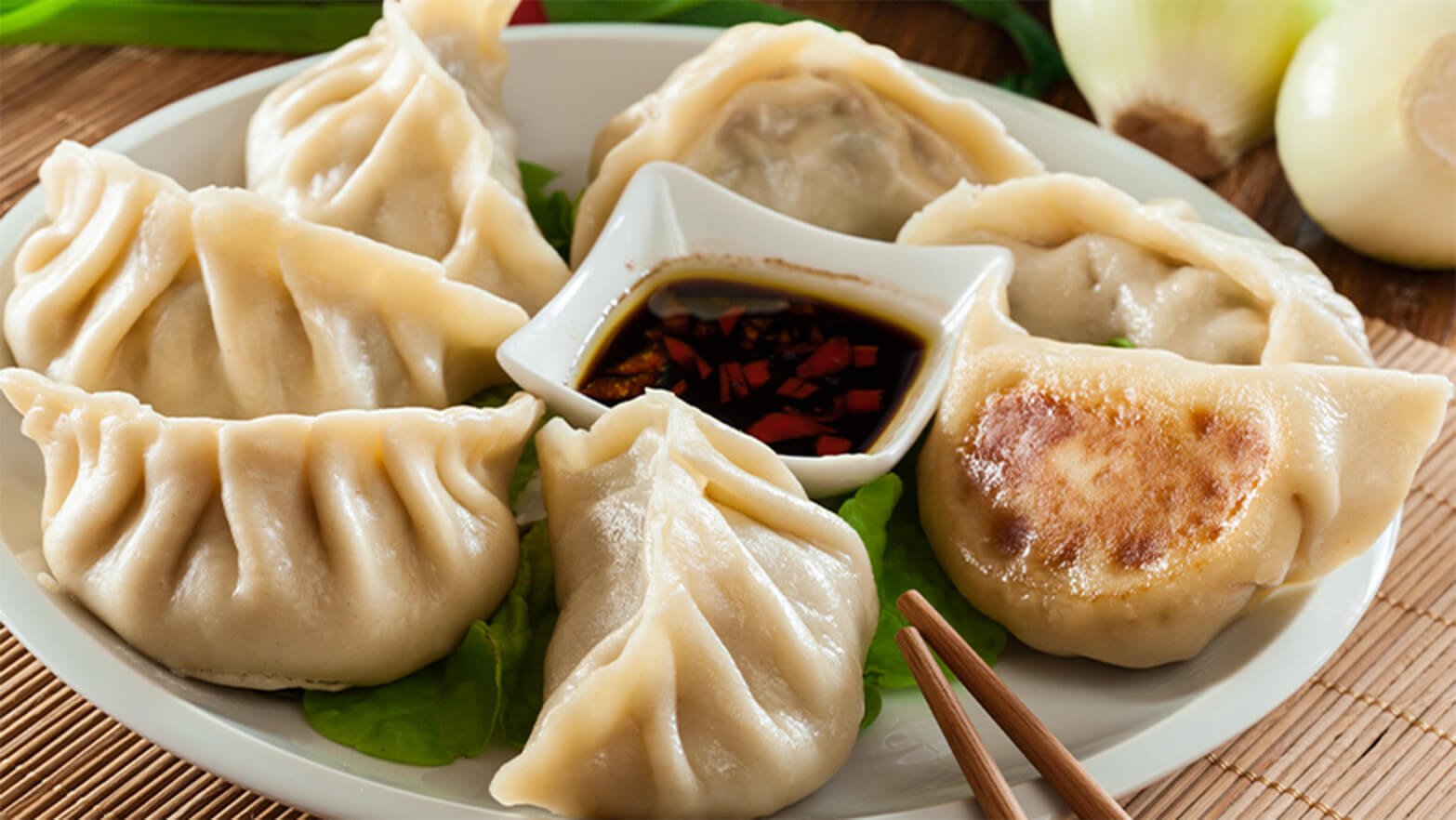 Plate of potstickers with dipping sauce and chopsticks