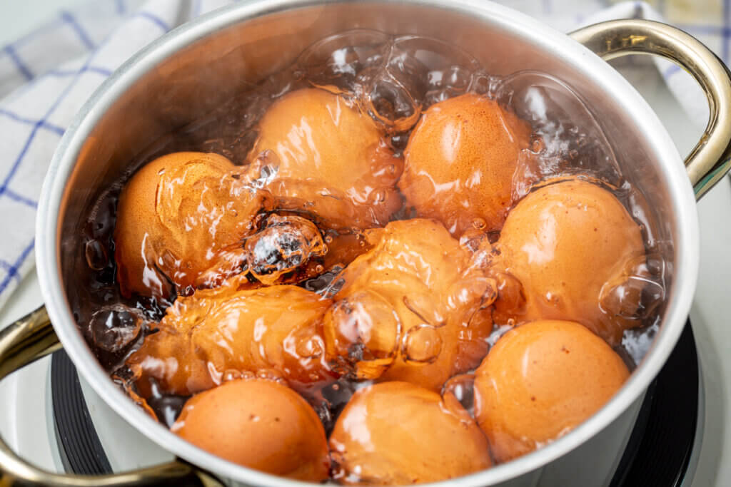 cooking brown chicken eggs in boiling water on electric stove.