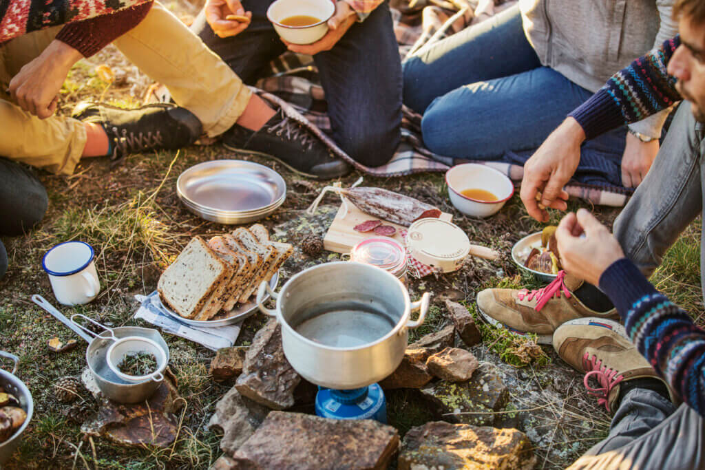 Low section of friends preparing breakfast at campsite