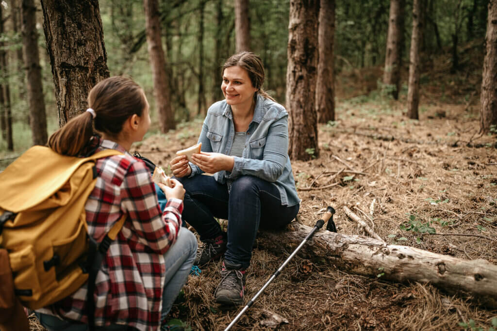 Mother and daughter eating sandwich on hiking tour