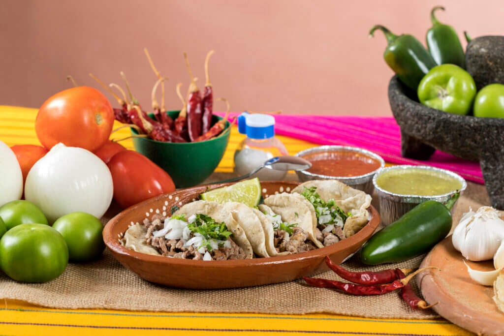 Typical Mexican food dishes with sauces on colorful table.
