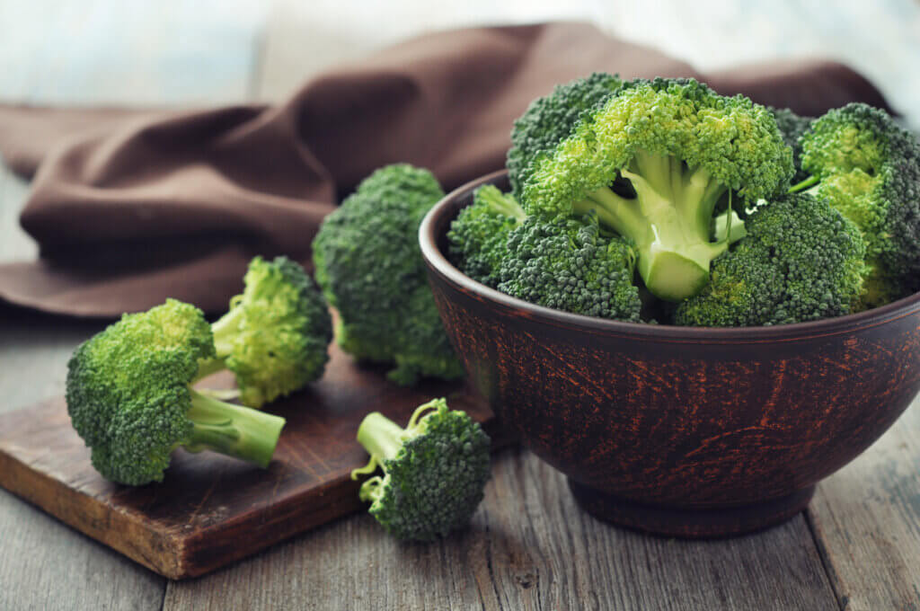 Bunch of fresh green broccoli on brown plate over wooden background