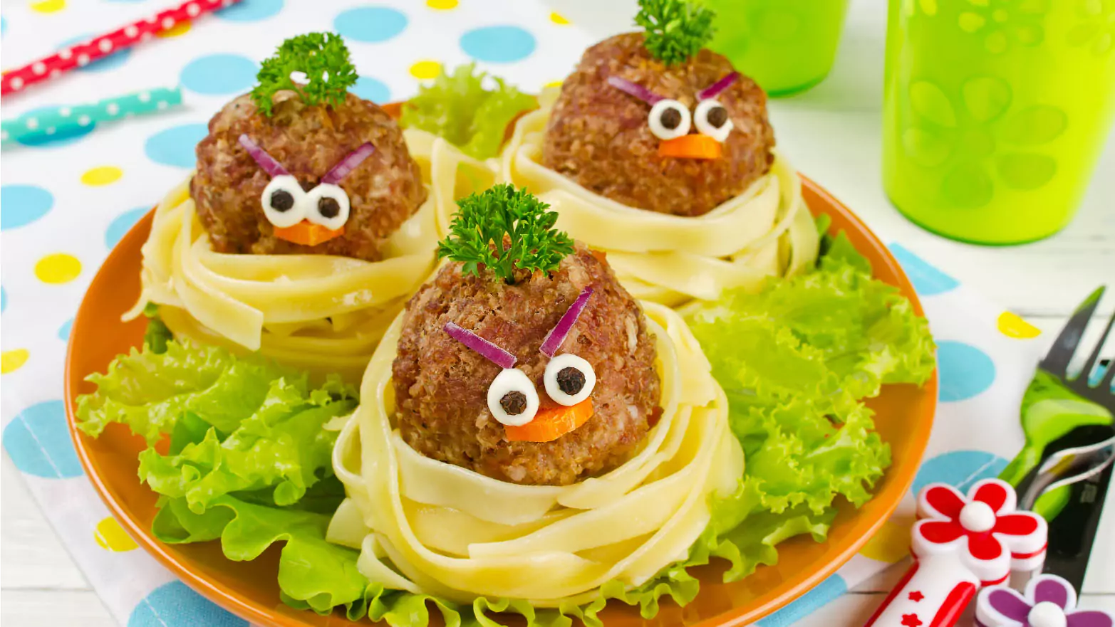 Meatballs wrapped in noodles with vegetables forming a bird face