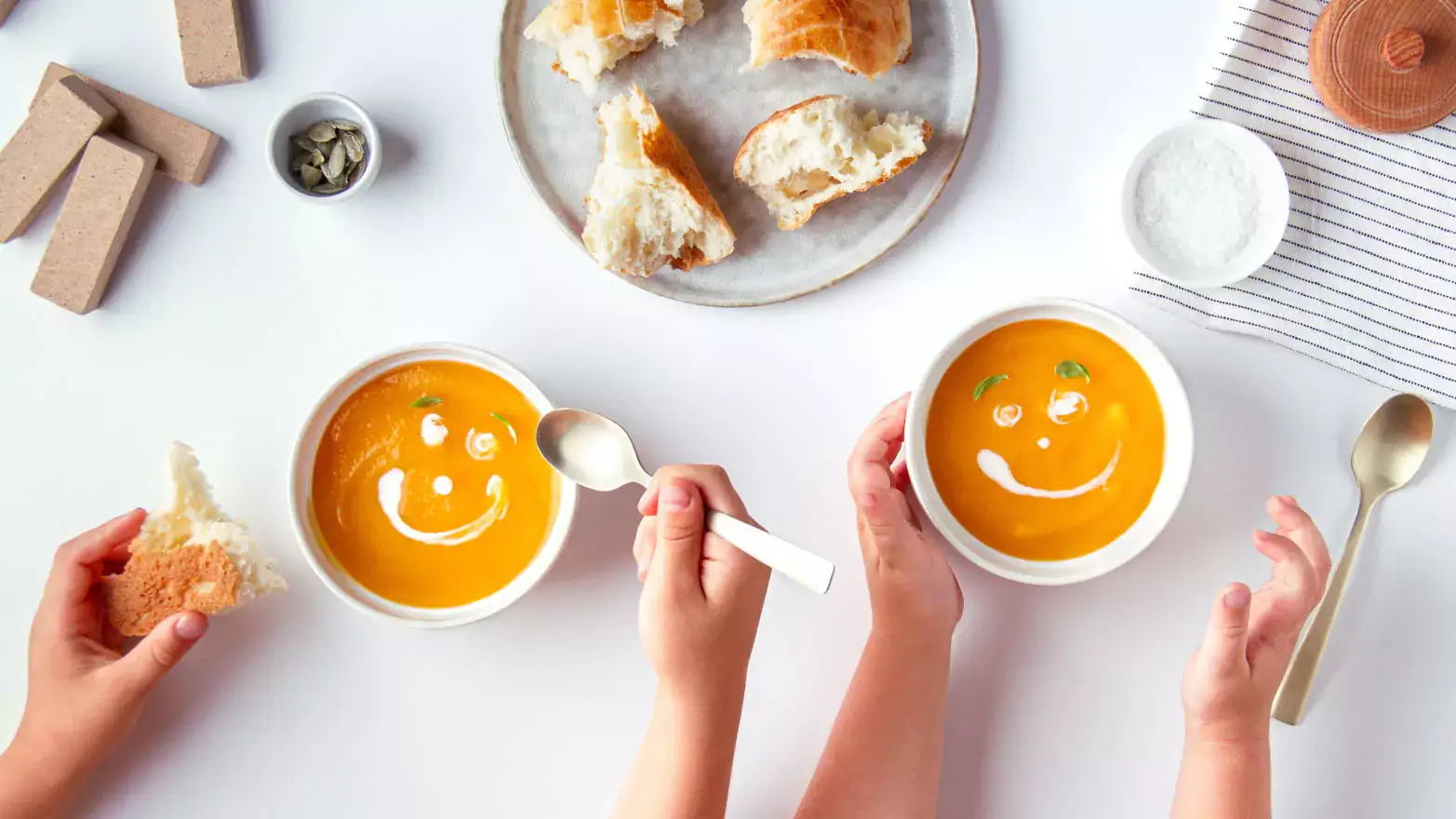 Two children enjoying bowls of tomato soup with bread and cream