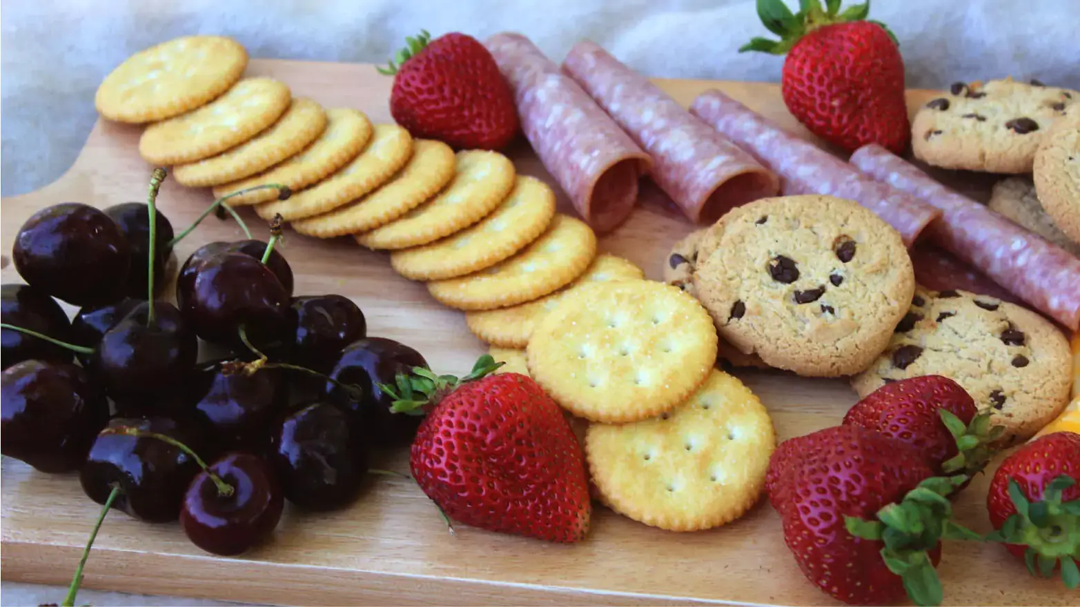 Simple kids charcuterie board with crackers, salami, fruit and cookies