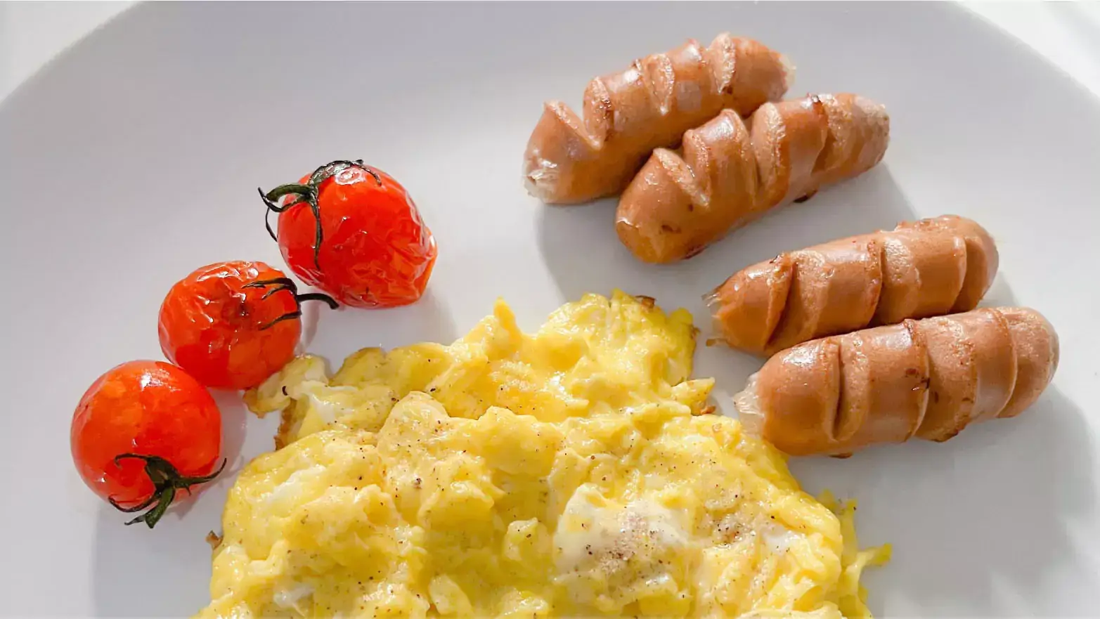 Healthy breakfast with scrambled eggs, sausage and tomatoes. 