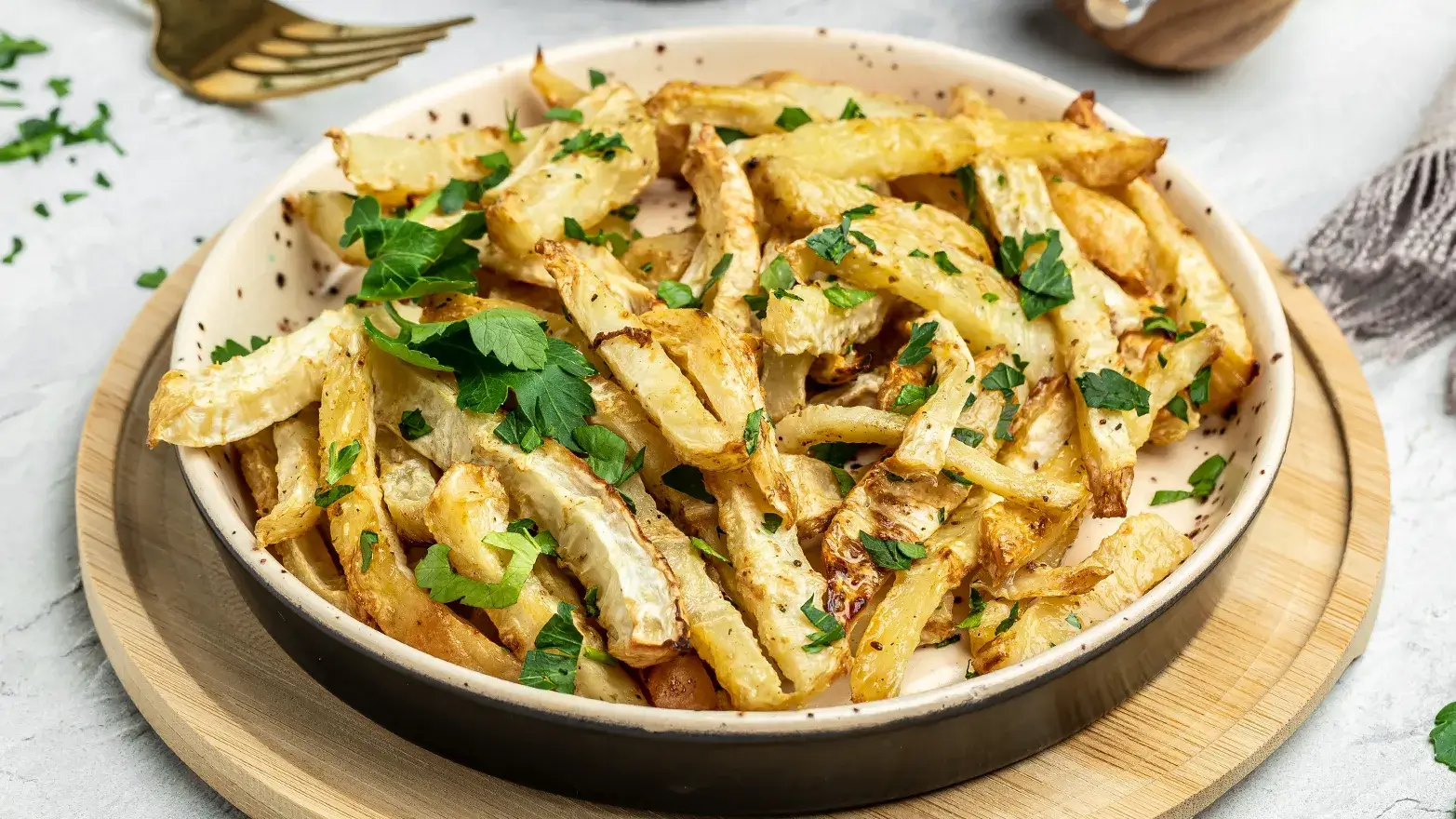 Plate of roasted parsnips seasoned with pepper and parsley with dipping sauce. 