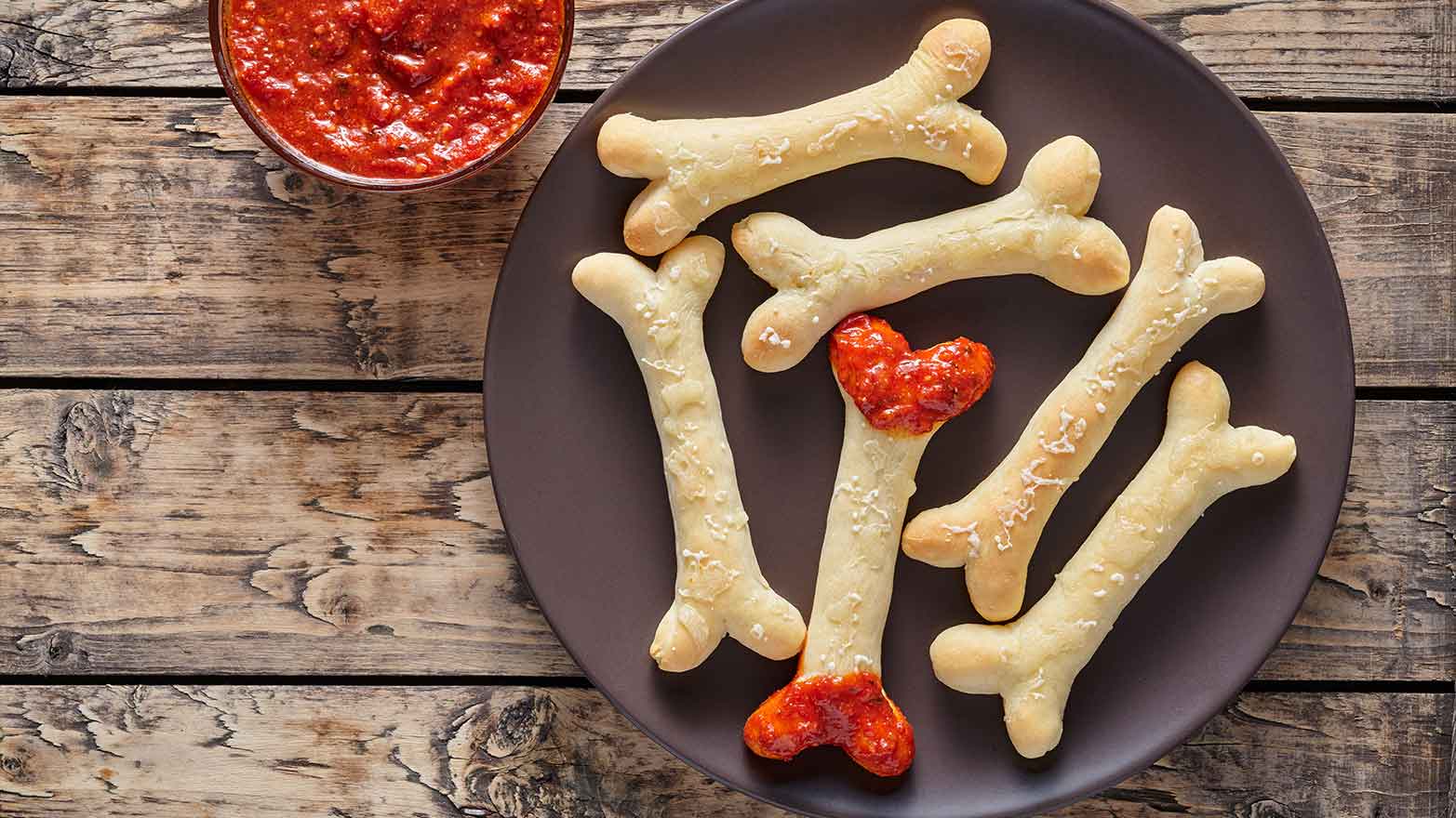 Breadsticks shaped like bones dipped in marinara