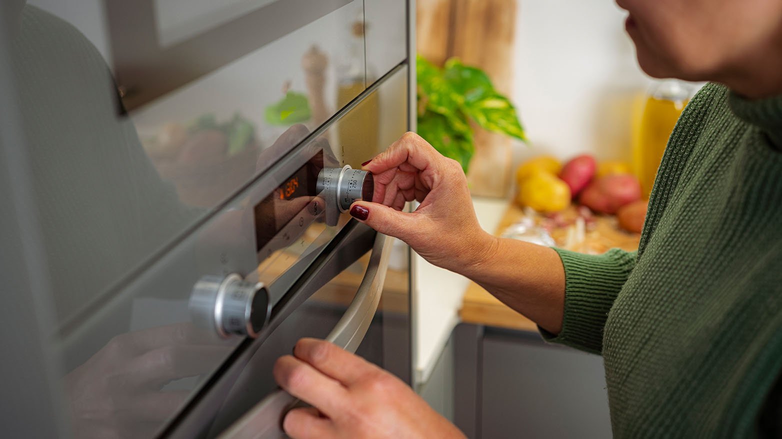 A person changing the oven temperature after using our oven temperature conversion chart.