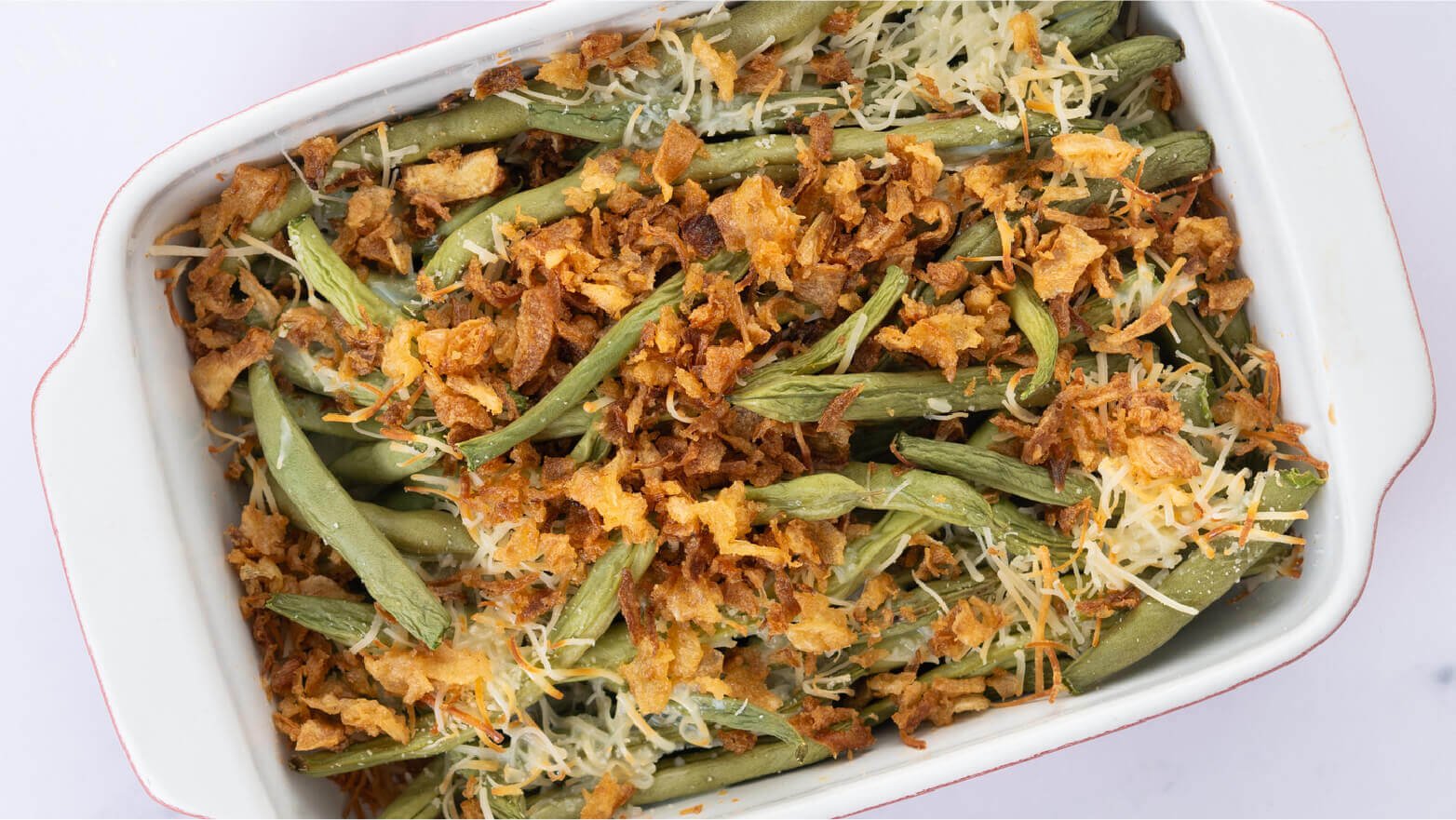 White baking dish with large serving of green bean casserole ready to serve at Shabbat dinner