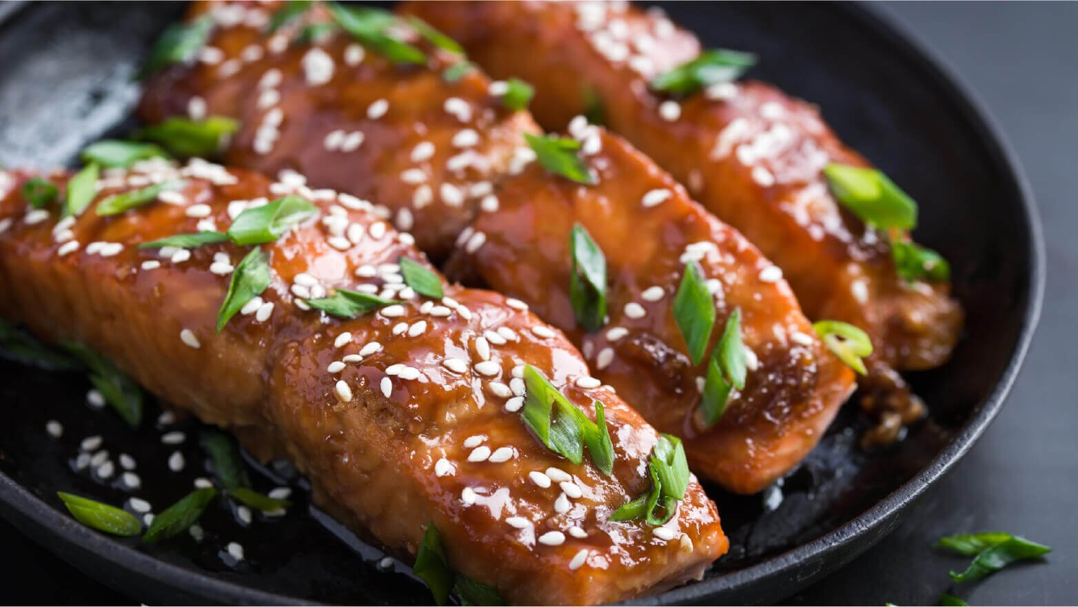 Maple salmon on a plate topped with green onion