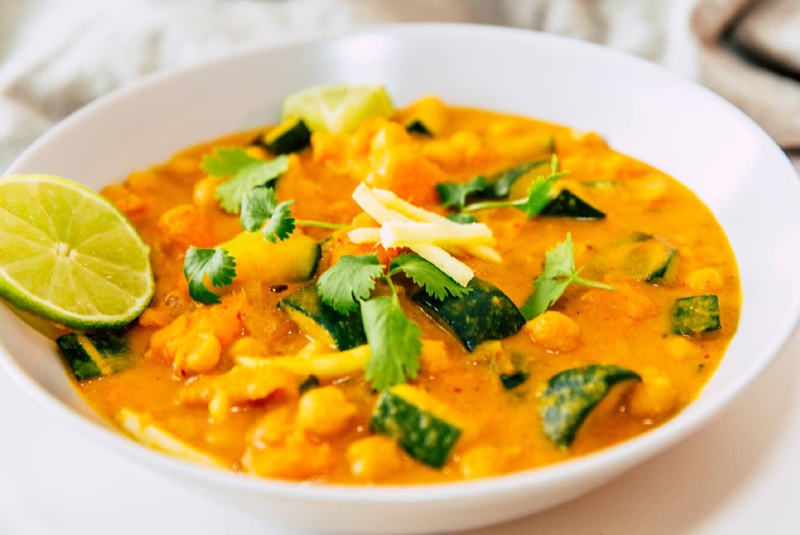 Large white bowl of vegetable curry with lime 